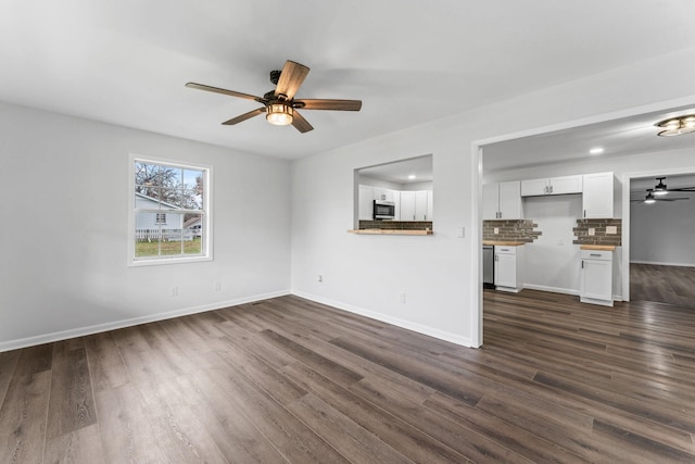 unfurnished living room featuring ceiling fan and dark wood-type flooring