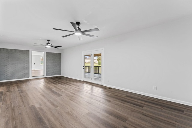 unfurnished room with dark hardwood / wood-style flooring, ceiling fan, and brick wall