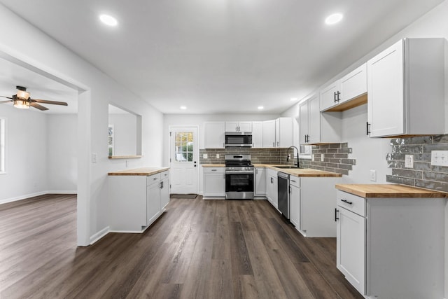 kitchen with backsplash, stainless steel appliances, white cabinetry, and butcher block counters