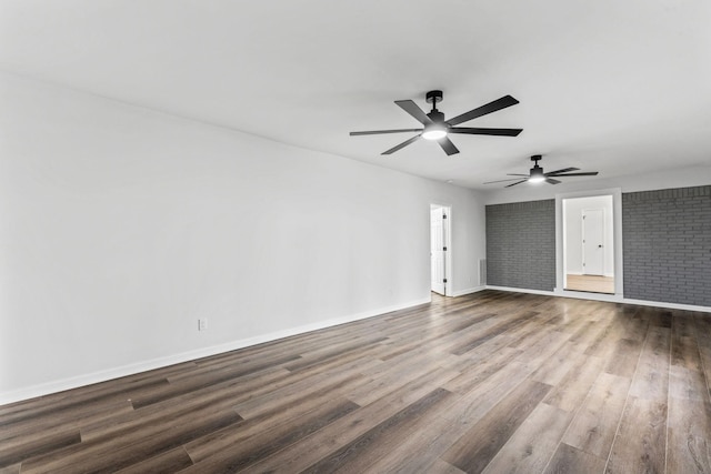 interior space featuring wood-type flooring, ceiling fan, and brick wall