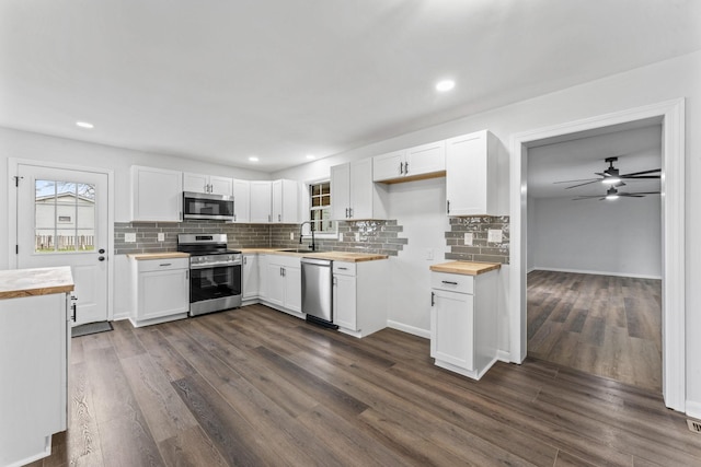 kitchen with wooden counters, stainless steel appliances, and white cabinetry