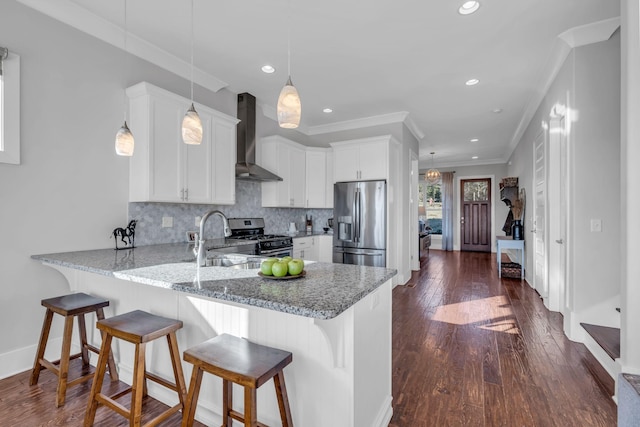 kitchen with pendant lighting, backsplash, wall chimney exhaust hood, white cabinetry, and stainless steel appliances