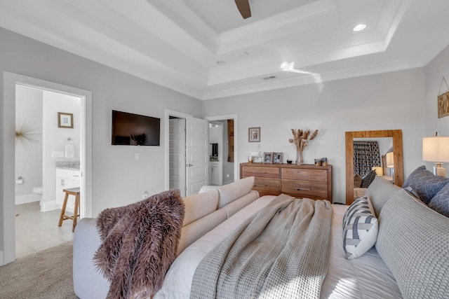 bedroom with connected bathroom, a tray ceiling, ceiling fan, and crown molding