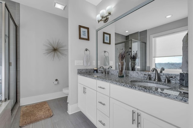 bathroom featuring tile patterned floors, vanity, toilet, and a shower with door