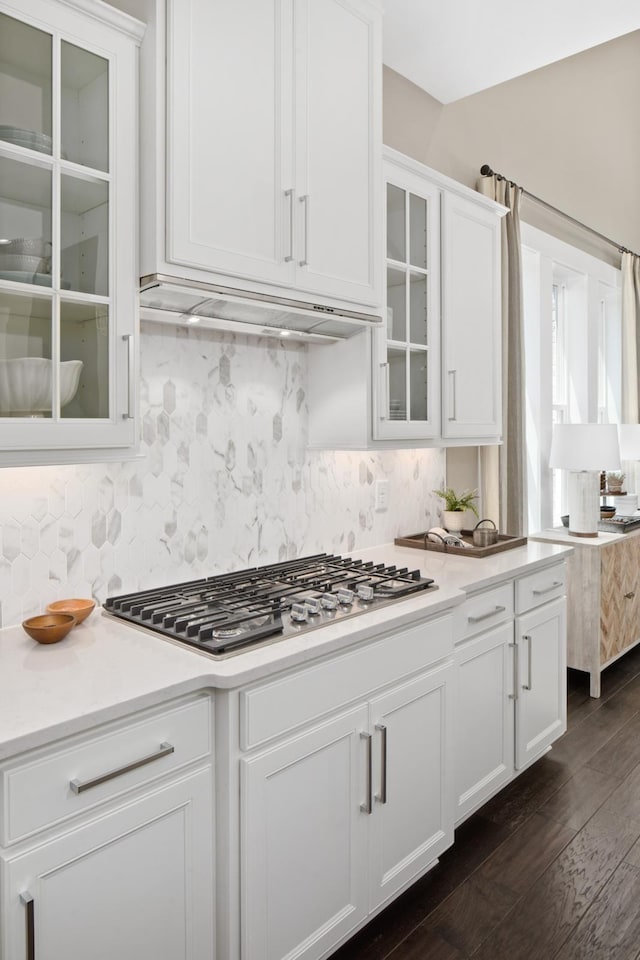 kitchen with tasteful backsplash, white cabinets, dark wood-type flooring, and stainless steel gas cooktop