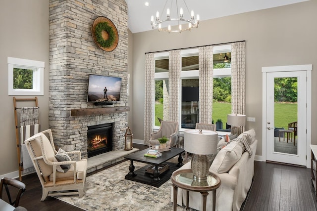 living room featuring a notable chandelier, dark hardwood / wood-style floors, a towering ceiling, and a fireplace