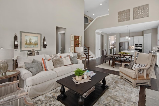 living room with hardwood / wood-style flooring, sink, and a high ceiling