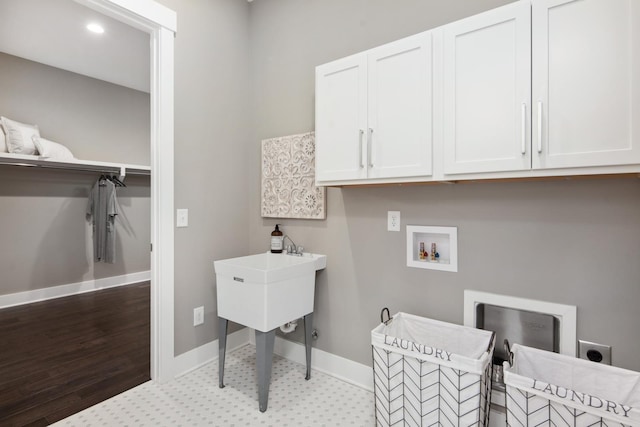 laundry room featuring electric dryer hookup, hookup for a washing machine, and cabinets