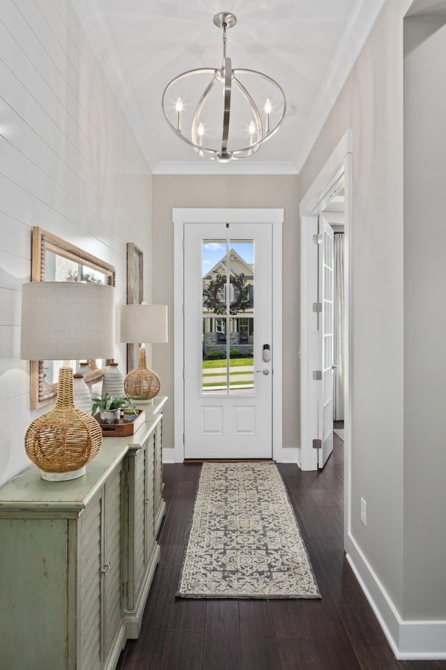 foyer entrance featuring ornamental molding, dark wood-type flooring, and an inviting chandelier