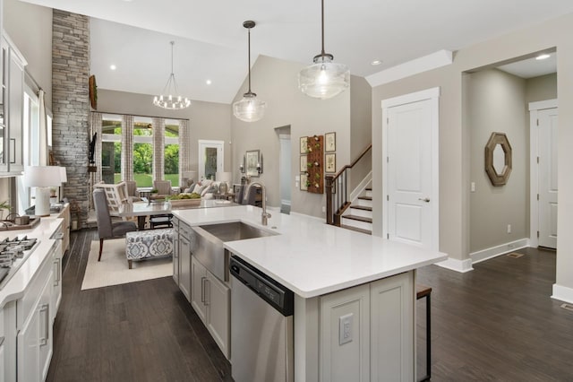 kitchen with a kitchen breakfast bar, sink, an island with sink, appliances with stainless steel finishes, and decorative light fixtures