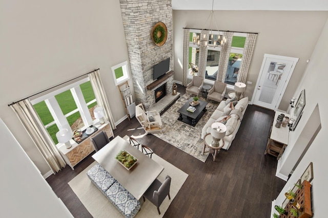 living room featuring a wealth of natural light, a fireplace, a high ceiling, and a notable chandelier