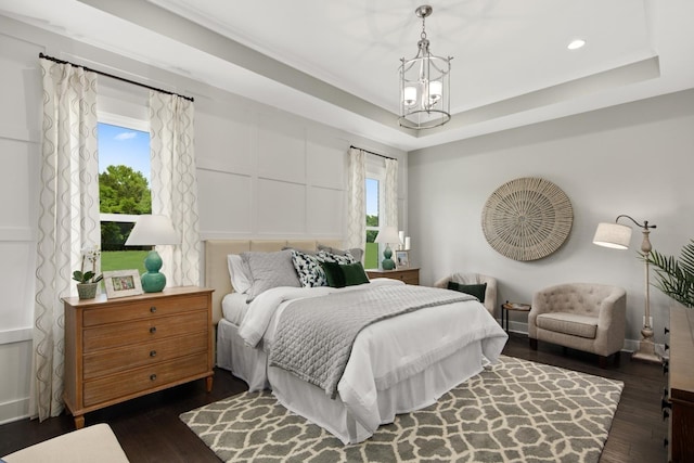 bedroom featuring a chandelier, dark hardwood / wood-style floors, and a raised ceiling