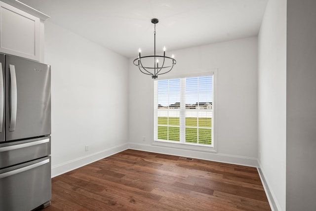 unfurnished dining area featuring dark wood-type flooring, an inviting chandelier, and a healthy amount of sunlight