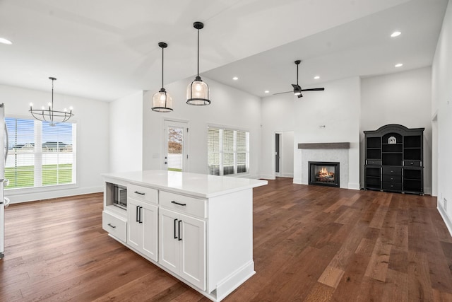 kitchen with a center island, stainless steel microwave, white cabinets, and pendant lighting