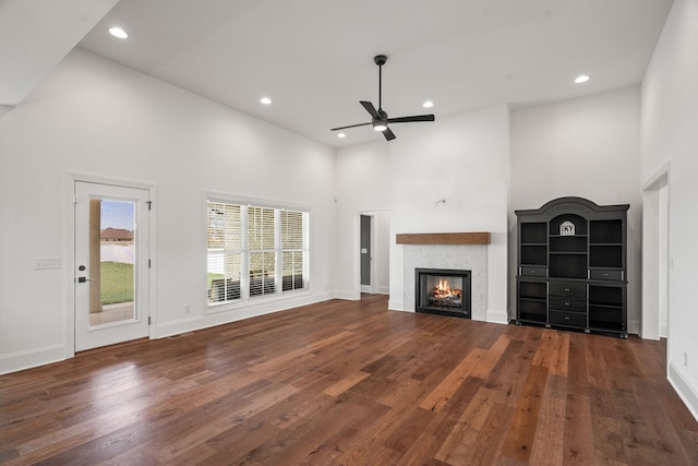 unfurnished living room with ceiling fan, dark hardwood / wood-style floors, and a high ceiling