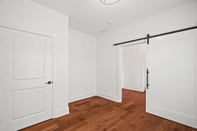 unfurnished room featuring a barn door and dark hardwood / wood-style flooring