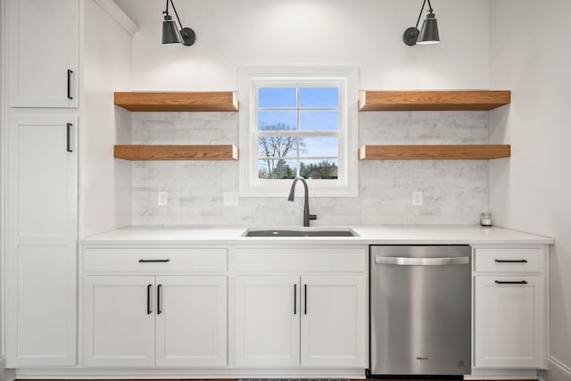 kitchen with decorative backsplash, white cabinetry, stainless steel dishwasher, and sink