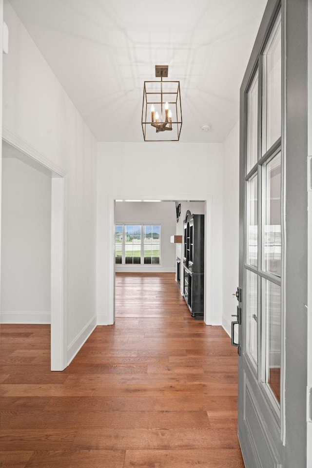 hallway with hardwood / wood-style flooring and a notable chandelier