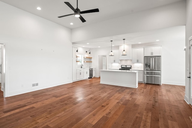 unfurnished living room with a towering ceiling, dark hardwood / wood-style flooring, ceiling fan, and sink