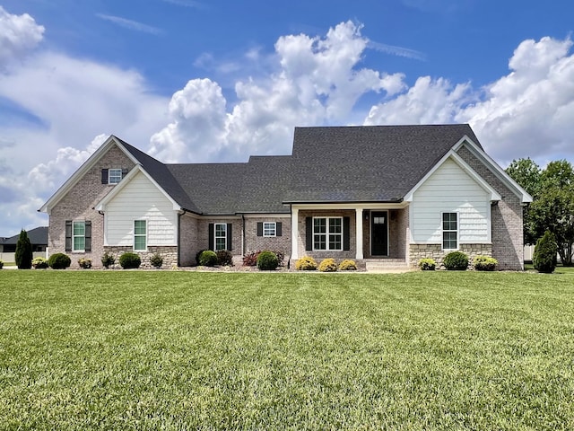 view of front of property featuring roof with shingles, a front lawn, and stone siding