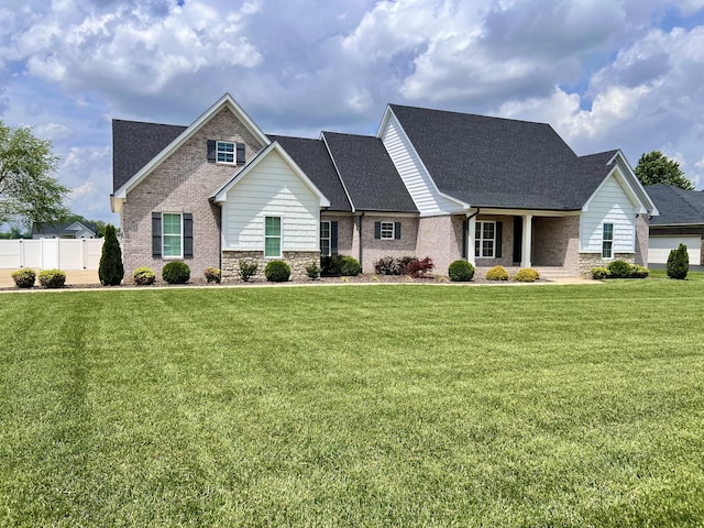 view of front of home featuring fence, a shingled roof, a front lawn, and brick siding