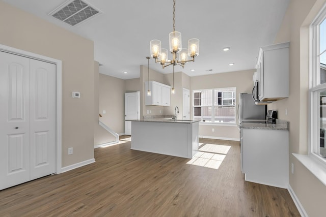 kitchen with pendant lighting, white cabinets, sink, a notable chandelier, and wood-type flooring