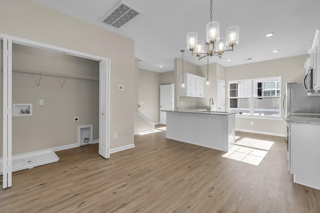 kitchen featuring light wood-type flooring, an inviting chandelier, white cabinetry, and hanging light fixtures