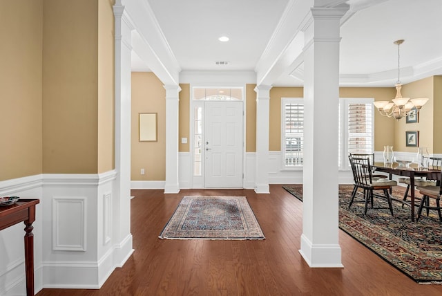 entrance foyer with dark hardwood / wood-style flooring, an inviting chandelier, and ornamental molding