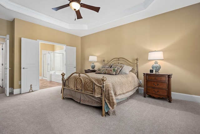 carpeted bedroom featuring a tray ceiling, ceiling fan, and ensuite bathroom