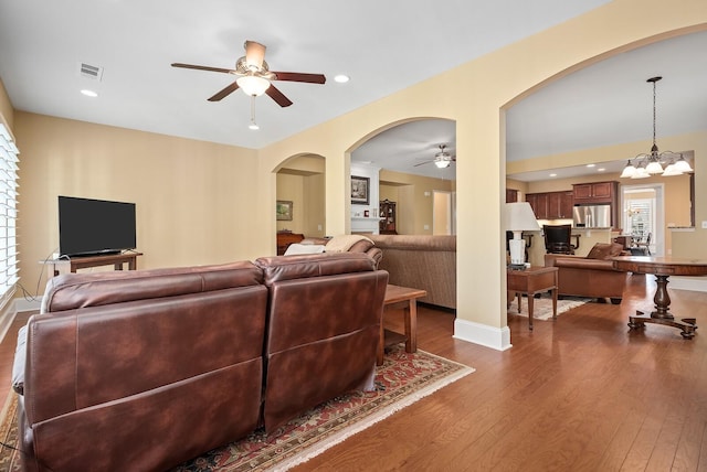 living room featuring wood-type flooring and ceiling fan with notable chandelier