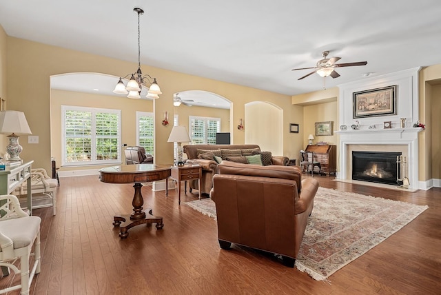 living room with ceiling fan with notable chandelier and dark hardwood / wood-style flooring