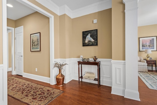 hall with dark hardwood / wood-style flooring, ornate columns, and crown molding