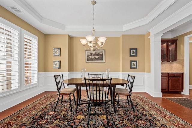 dining space with an inviting chandelier, crown molding, and a tray ceiling