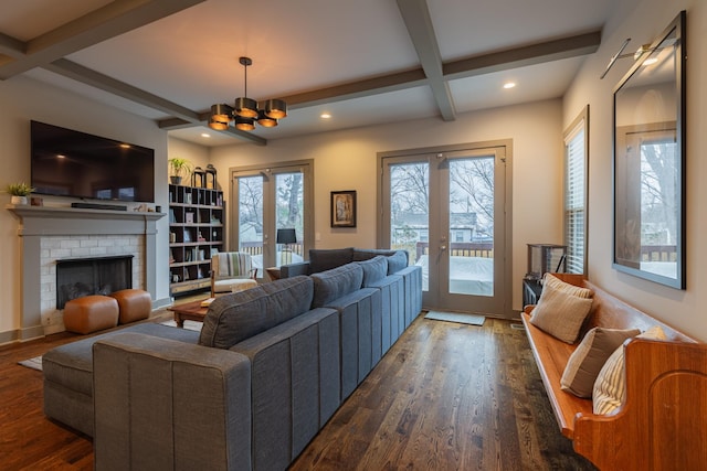 living room featuring beam ceiling, french doors, a brick fireplace, dark hardwood / wood-style flooring, and a notable chandelier