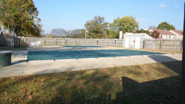 view of swimming pool featuring a patio, a storage unit, and a lawn