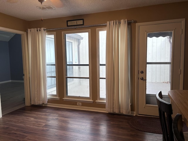 doorway to outside with plenty of natural light, dark hardwood / wood-style flooring, and a textured ceiling