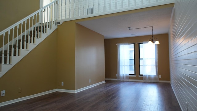 unfurnished living room with a notable chandelier and dark hardwood / wood-style floors