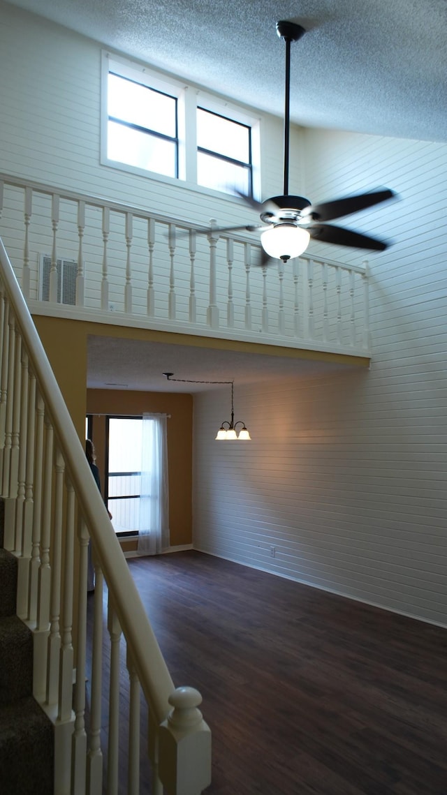 stairway with a textured ceiling, a healthy amount of sunlight, ceiling fan with notable chandelier, and wood-type flooring