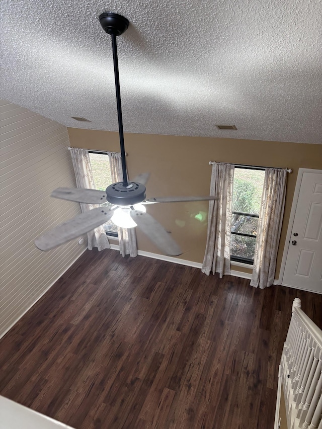 unfurnished dining area with dark hardwood / wood-style flooring, a textured ceiling, and wood walls