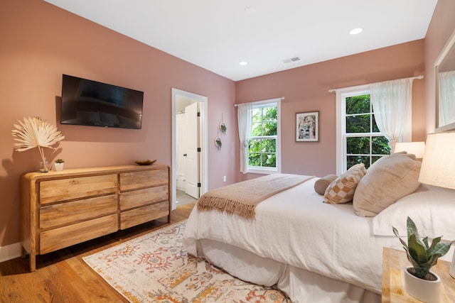 bedroom with connected bathroom and light wood-type flooring