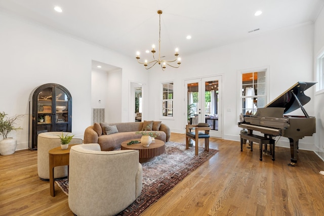 living room featuring ornamental molding, french doors, light wood-type flooring, and a notable chandelier