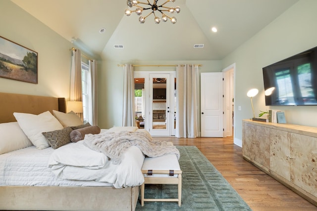 bedroom featuring lofted ceiling, light hardwood / wood-style flooring, and an inviting chandelier