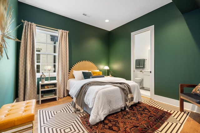 bedroom featuring ensuite bath and light hardwood / wood-style floors