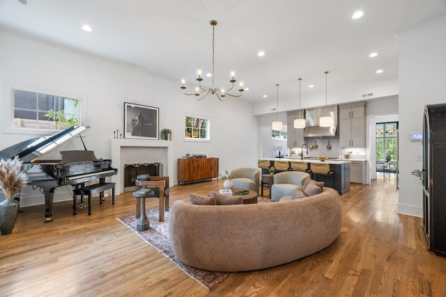 living room with light hardwood / wood-style floors, a notable chandelier, and sink