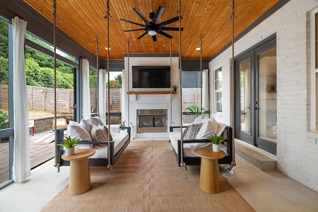 sunroom with an outdoor brick fireplace, ceiling fan, and wood ceiling