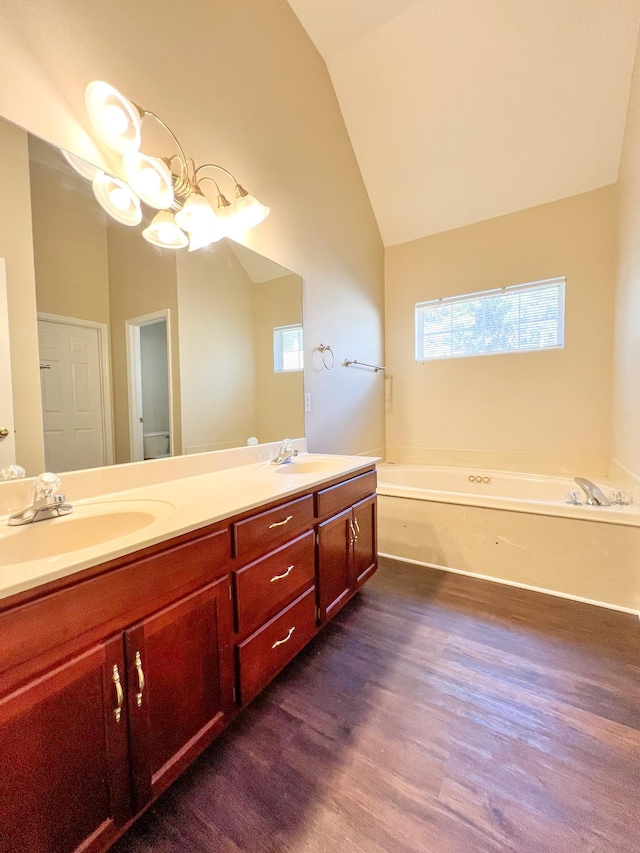 bathroom with a tub, vanity, wood-type flooring, and vaulted ceiling