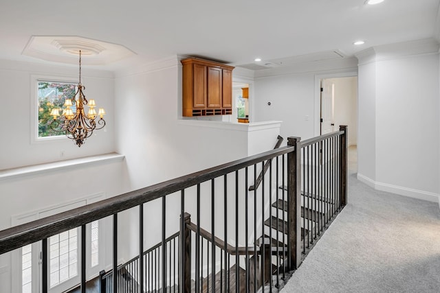 corridor with carpet, crown molding, and an inviting chandelier