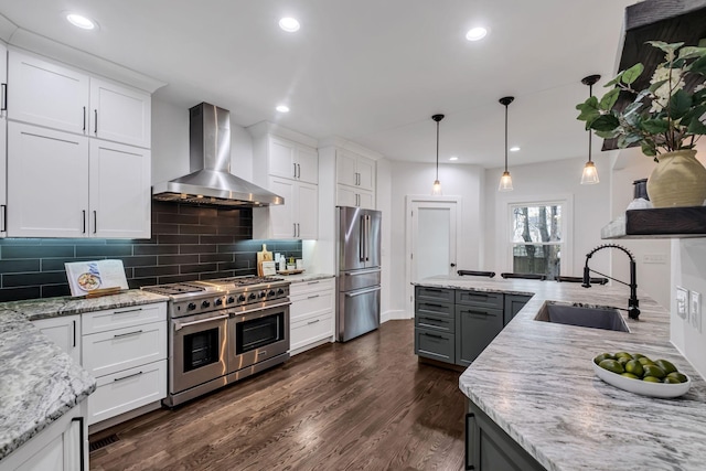 kitchen featuring white cabinets, appliances with stainless steel finishes, wall chimney exhaust hood, and sink