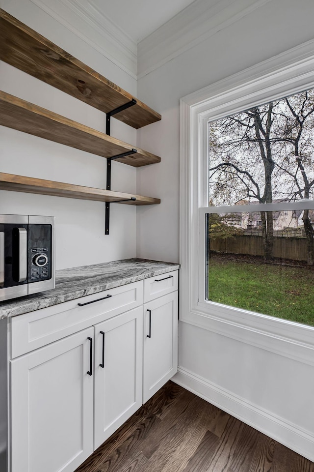 bar featuring white cabinets, dark hardwood / wood-style flooring, light stone counters, and ornamental molding