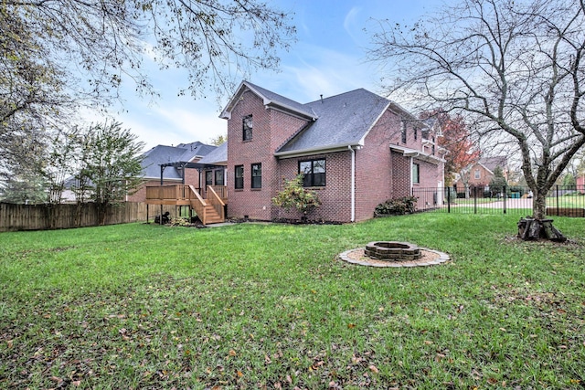 back of property featuring a yard, an outdoor fire pit, and a wooden deck